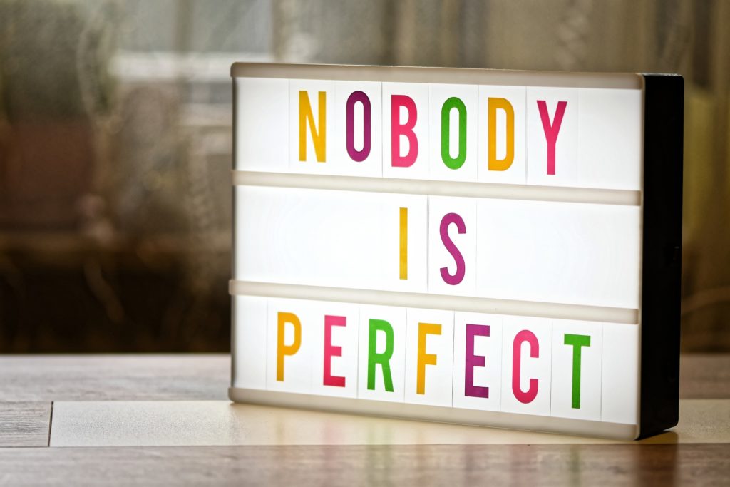 A lit-up sign that reads 'nobody is perfect', aimed at affirming readers with a positive quote that reassures them it's okay to not have the perfect writing routine
